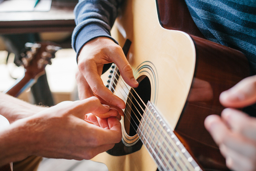 teacher showing student guitar chord