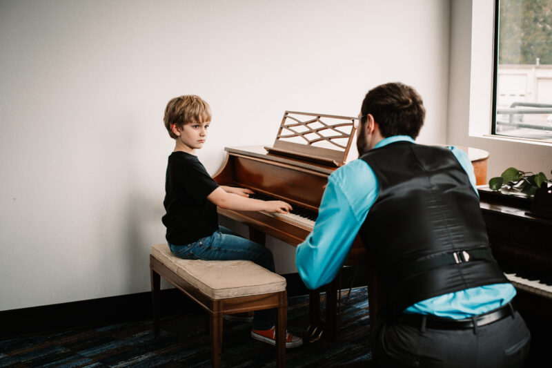 Male teacher with male student at pianos