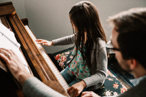 Male teacher with female student at piano